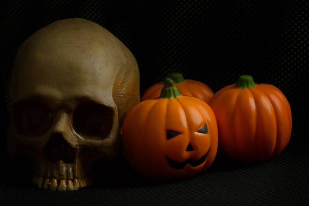 Halloween-Kürbis Jack und Totenkopf im schwarzen Feiertags-Hintergrundbild. - Foto, Bild