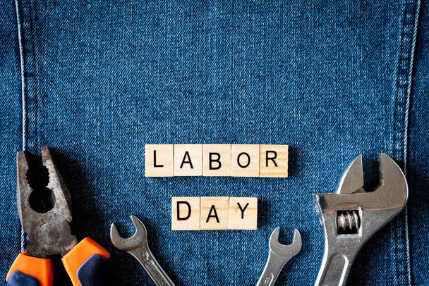 USA Labor day concept, First Monday in September. Different kinds on wrenches, handy tools, America flag and wooden tag on blue jeans background. - Foto, afbeelding