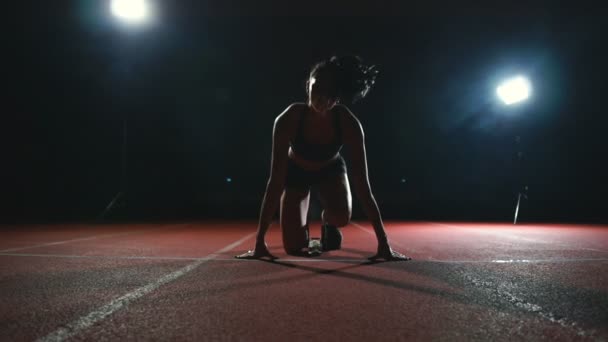 Slank jong meisje atleet is in staat om de begint te lopen in de pads op het spoor in slow motion - Video
