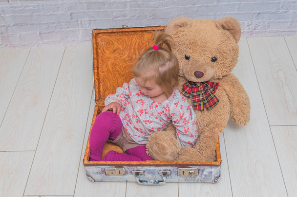 girl, child with bear and suitcase on white brick wall background - Fotoğraf, Görsel