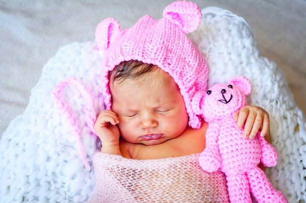 Édes kaukázusi újszülött baba lány egy aranyos rózsaszín kalapot átölelve a maci füle. Újszülött fotó ülés studio stock kép.  - Fotó, kép