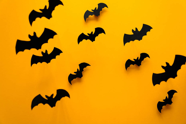 Black paper bats flying on yellow background. Halloween concept. Paper cut style. Top view - Zdjęcie, obraz