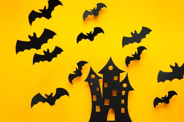 Scary castle silhouette and black paper bats flying on yellow background. Halloween concept. Paper cut style. Top view - Foto, Imagem