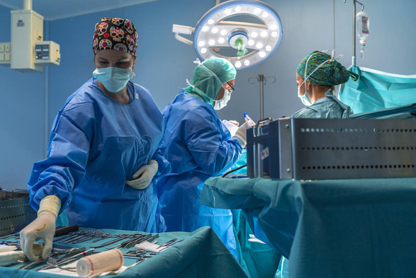 Le chirurgien, l'assistante chirurgicale et l'infirmière qui travaillent dans la salle d'opération peuvent voir le matériel chirurgical. Ils sont éclairés par la lumière de la salle d'opération
. - Photo, image