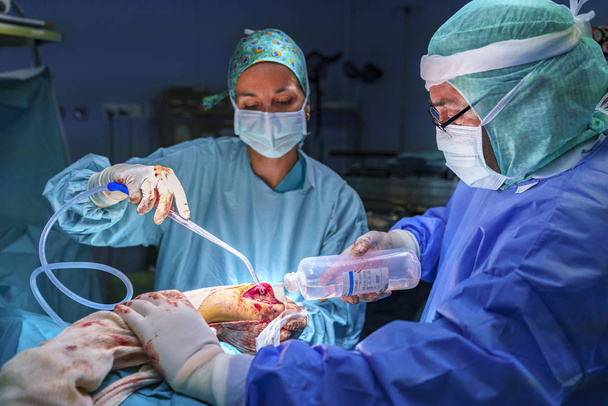 Chirurgo, assistente chirurgico e infermiere che lavorano in sala operatoria possono vedere il materiale chirurgico. Sono illuminati dalla luce della sala operatoria
. - Foto, immagini