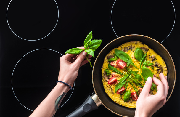 plan recadré d'omelette de cuisine femme dans une poêle à frire sur cuisinière noire
 - Photo, image