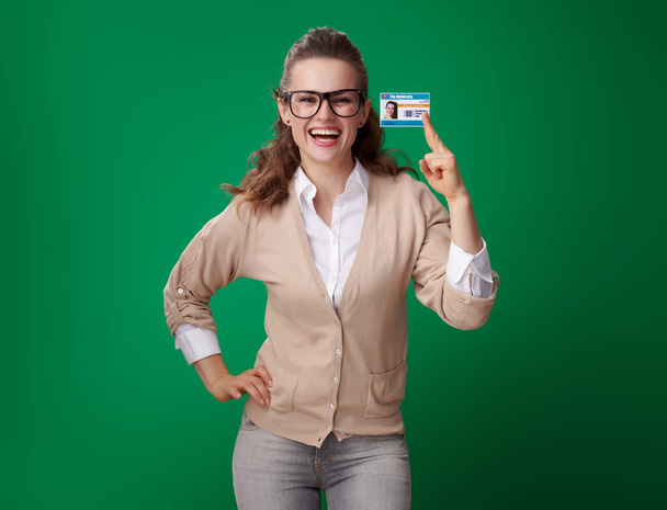 attractive student woman laughing and showing student card against green background  - Foto, Imagem