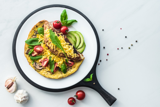 food composition with healthy omelette on wooden board on white marble tabletop - Foto, afbeelding