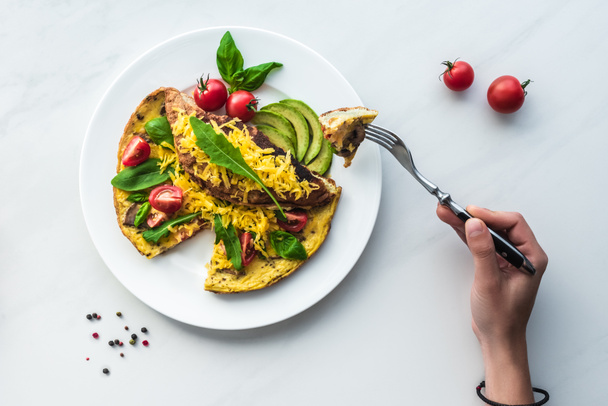 partial view of woman with fork in hand at tabletop with homemade omelette for breakfast - Fotoğraf, Görsel
