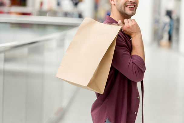 cropped image of young man holding paper bag at shopping mall  - 写真・画像