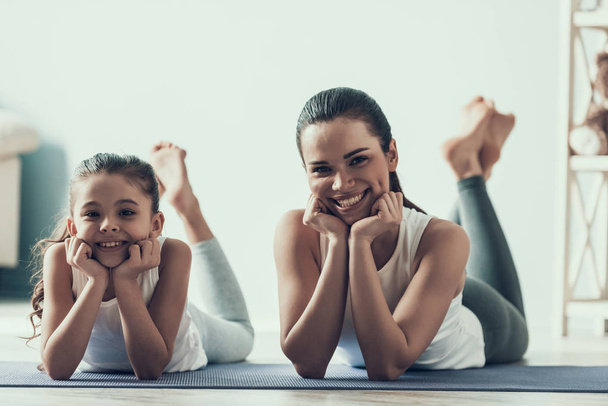 Young Woman and Little Girl Resting after Exercise. Beautiful Young Mother and Adorable Little Daughter Lying on Yoga mat. Mother and Daughter Together at Home. Healthy Lifestyle - Fotó, kép