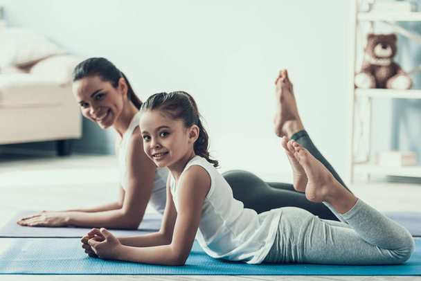 Young Woman and Little Girl Resting after Exercise. Beautiful Young Mother and Adorable Little Daughter Lying on Yoga mat. Mother and Daughter Together at Home. Healthy Lifestyle - Fotografie, Obrázek