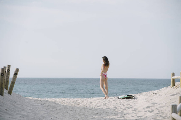 Sörf tahtası tutan bir plajda bir sörfçü kadın portresi - Fotoğraf, Görsel