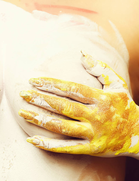 topless woman body covering her sexy breast with hand smeared in golden glister and white paint. - Foto, immagini