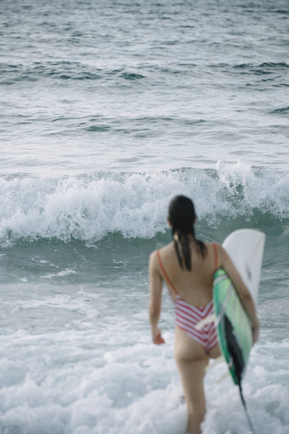 Portréja egy szörfös nő a gazdaság egy szörfdeszka strandon - Fotó, kép