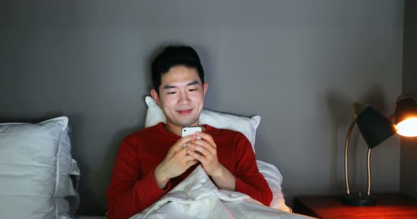 Man using mobile phone on bed at home 4k - Záběry, video