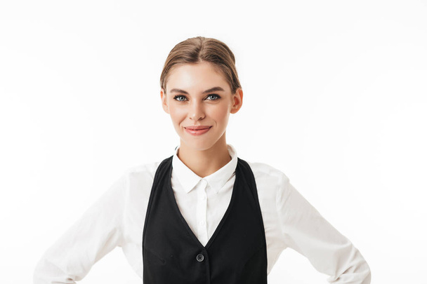 Young smiling woman in black vest and white shirt dreamily looking in camera over white background - Фото, зображення