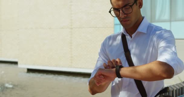 Man checking his smartwatch on street in the city 4k - Felvétel, videó