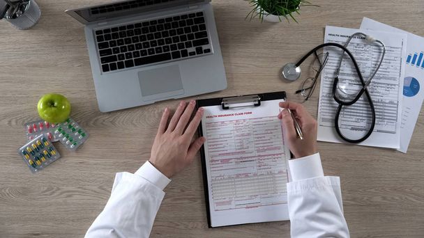 Praktický lékař čtení zdravotního pojištění formulář žádosti před podepsáním pohled shora - Fotografie, Obrázek