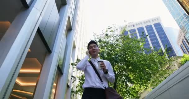 Low angle view of man talking on mobile phone while walking on street 4k - 映像、動画