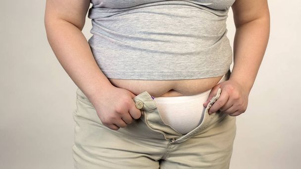 Overweight female trying to button trousers, obesity, saggy belly, plus size - Foto, immagini