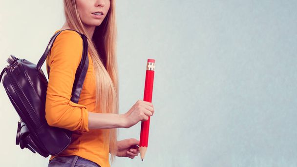 Teenage girl going to school or college wearing backpack and holding big pencil. - Foto, Imagen
