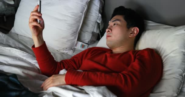 Man using mobile phone on bed at home 4k - Filmagem, Vídeo