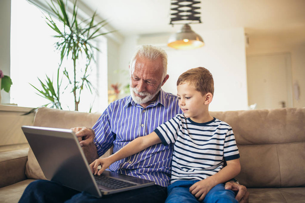 Nagyapa és unokája laptop együttes használata - Fotó, kép