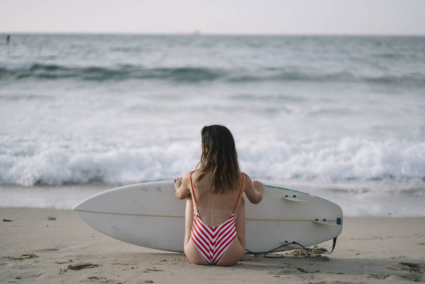 Porträt einer Surferin am Strand mit einem Surfbrett - Foto, Bild