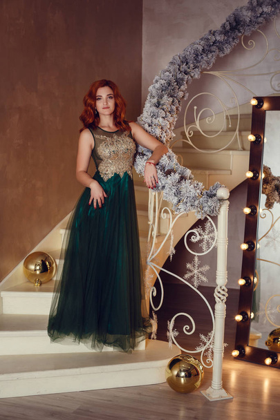 schöne Frau in luxuriösem Kleid hat ein Geschenk unter dem Weihnachtsbaum gefunden. das Konzept der exquisiten Feier des neuen Jahres - Foto, Bild