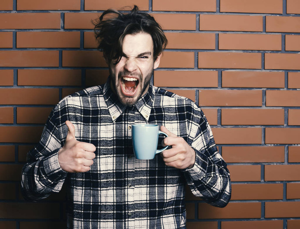 handsome guy holding cup on brick wall background - Foto, immagini