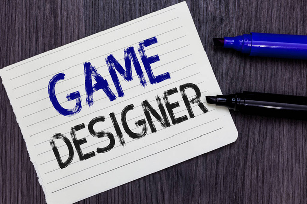 Writing note showing Game Designer. Business photo showcasing Campaigner Pixel Scripting Programmers Consoles 3D Graphics Notebook Paper Reminder Communicating ideas Markers Wooden background. - Photo, Image
