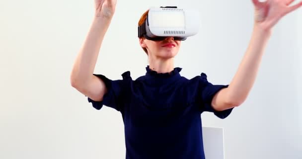 Woman using virtual reality headset on chair against white background 4k - Filmati, video