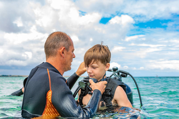 Un homme en costume de plongée prépare un garçon à plonger
 - Photo, image