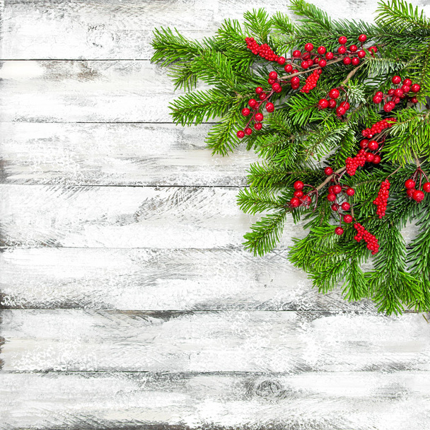 Karácsonyfa ágai a piros bogyós gyümölcsök dekoráció fehér fa textúra. Téli ünnepek háttér - Fotó, kép