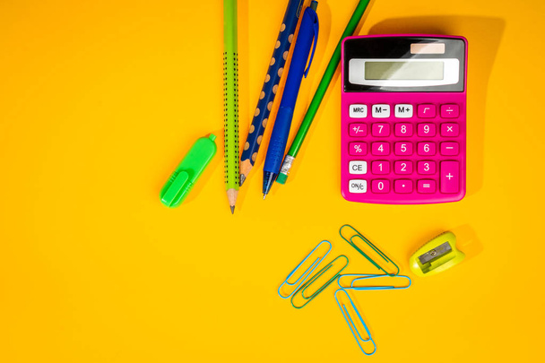 fundo amarelo com um lápis de cor, calculadora, régua e canetas de feltro
 - Foto, Imagem