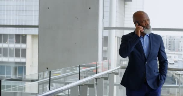Businessman talking on mobile phone while walking at office 4k - Metraje, vídeo