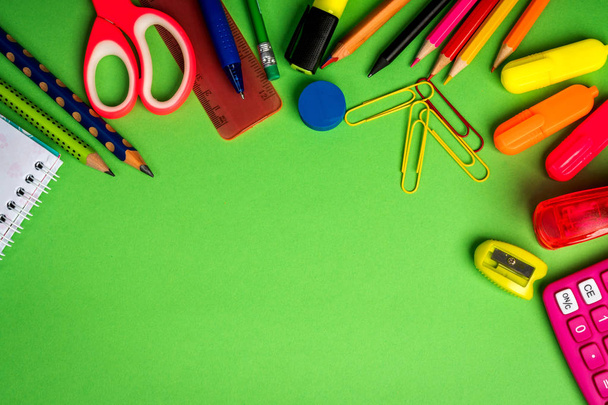 groene achtergrond met een potloden, rekenmachine, liniaal en vilt-tip pennen - Foto, afbeelding