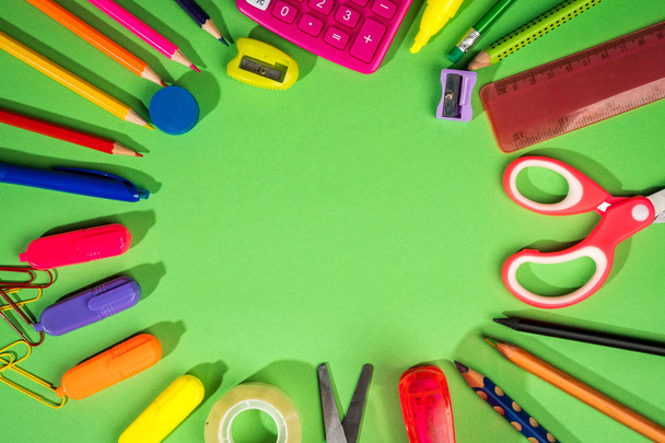 groene achtergrond met een potloden, rekenmachine, liniaal en vilt-tip pennen - Foto, afbeelding