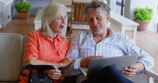 Senior couple discussing over laptop on sofa at home 4k - Кадри, відео