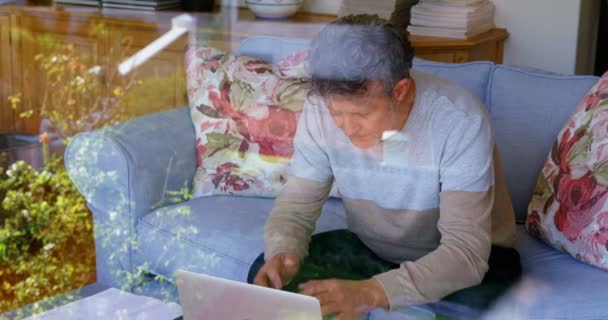 Worried senior man using laptop on sofa at home 4k - Filmati, video