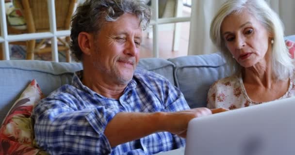 Senior couple discussing over laptop on sofa at home 4k - Video, Çekim