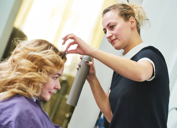 hairdo in beauty salon. hairdresser fixing hair with hairspray - Photo, Image