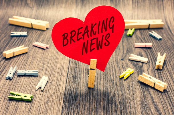 Word writing text Breaking News. Business concept for Special Report Announcement Happening Current Issue Flashnews Clothespin holding red paper heart several clothespins wooden floor romance. - Photo, Image
