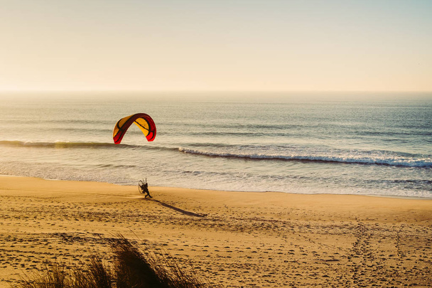 Powered paraglind hobbist practicing on a beach during a sunset - Photo, Image
