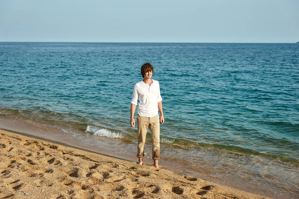 Handsome young man having fun on the beach by the sea - Fotoğraf, Görsel