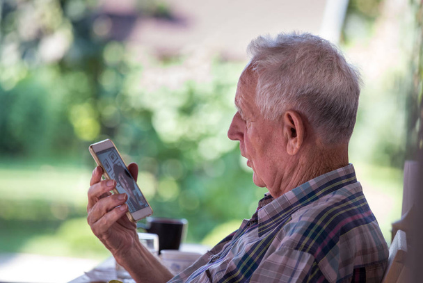 Homme âgé confus assis dans le parc et parlant sur son téléphone portable
 - Photo, image