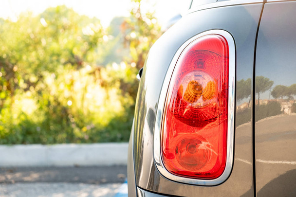 Красная задняя фара серого автомобиля летом. Задний фонарь
 - Фото, изображение