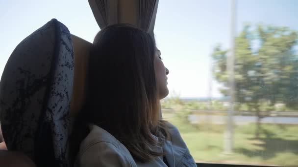 Jonge brunette vrouw reizen met de bus, u geniet van het uitzicht door het raam - Video