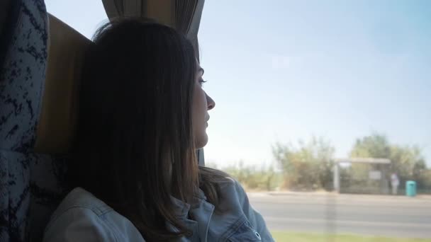 Fiatal barna nő utazás autóbusszal, gyönyörködnek az ablakon - Felvétel, videó